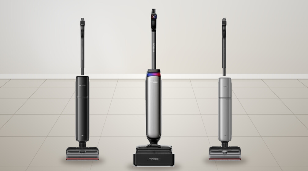 Three cordless steam mops standing on a tiled floor