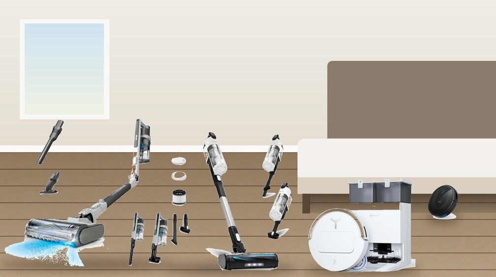 Slim robot vacuums and lay-flat stick vacuums on a wood floor beside a low bed